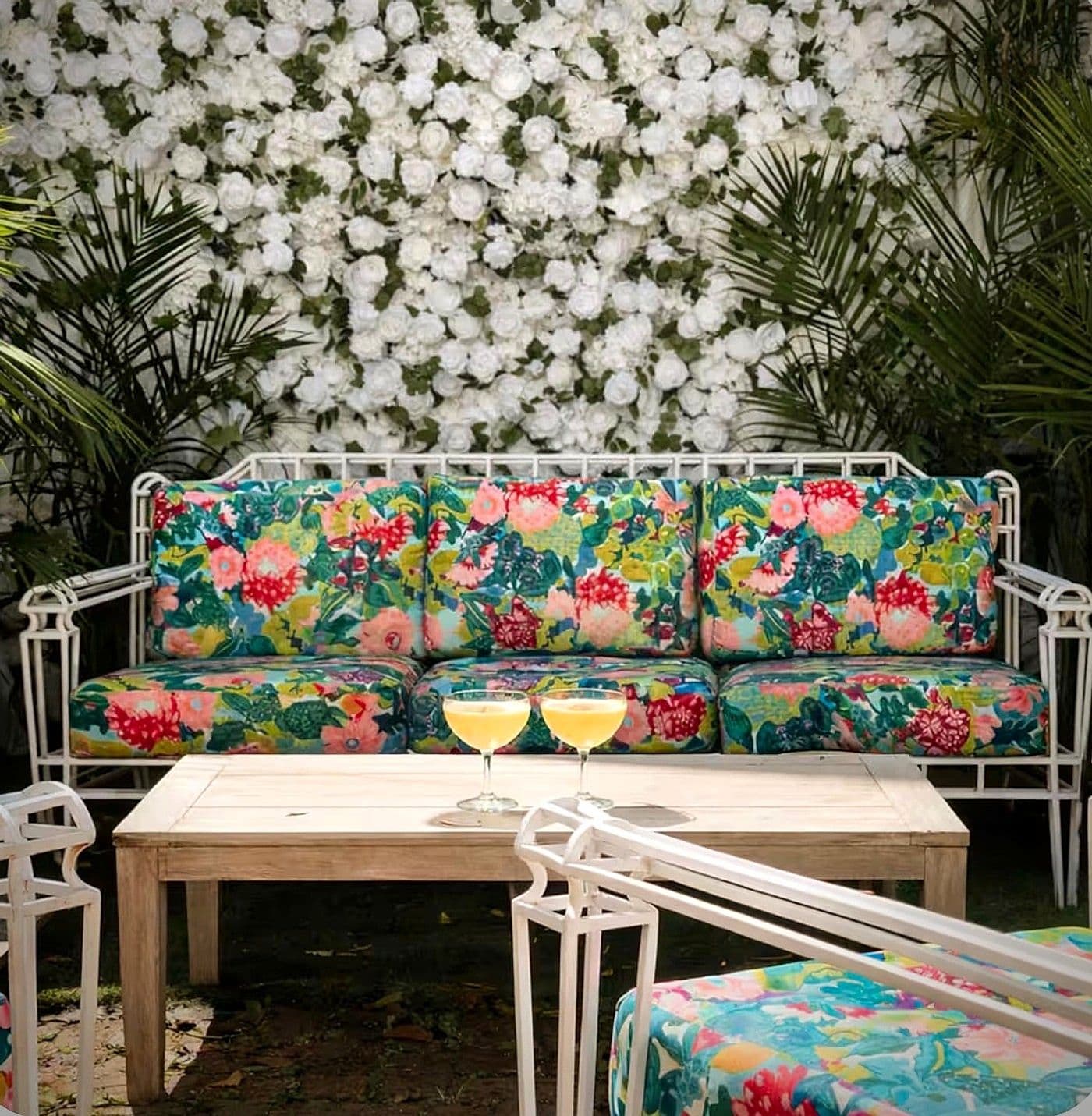 The courtyard at Maison St. LaFleur, with a flower wall, string lights, and lounge seating